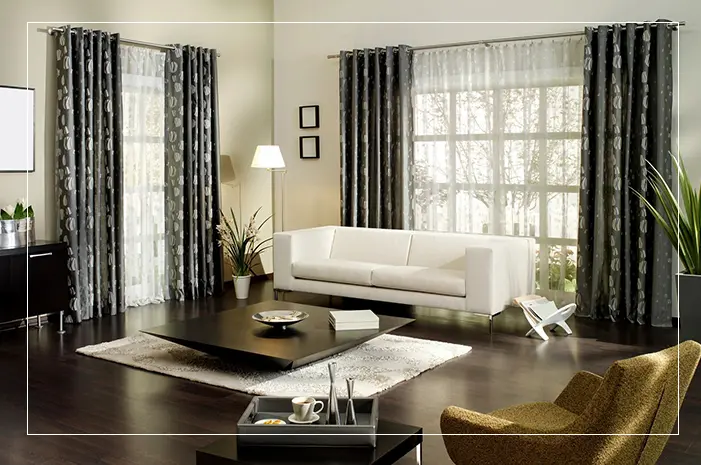 A living room with white furniture and black curtains.
