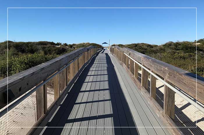 A long wooden bridge with a blue sky in the background.